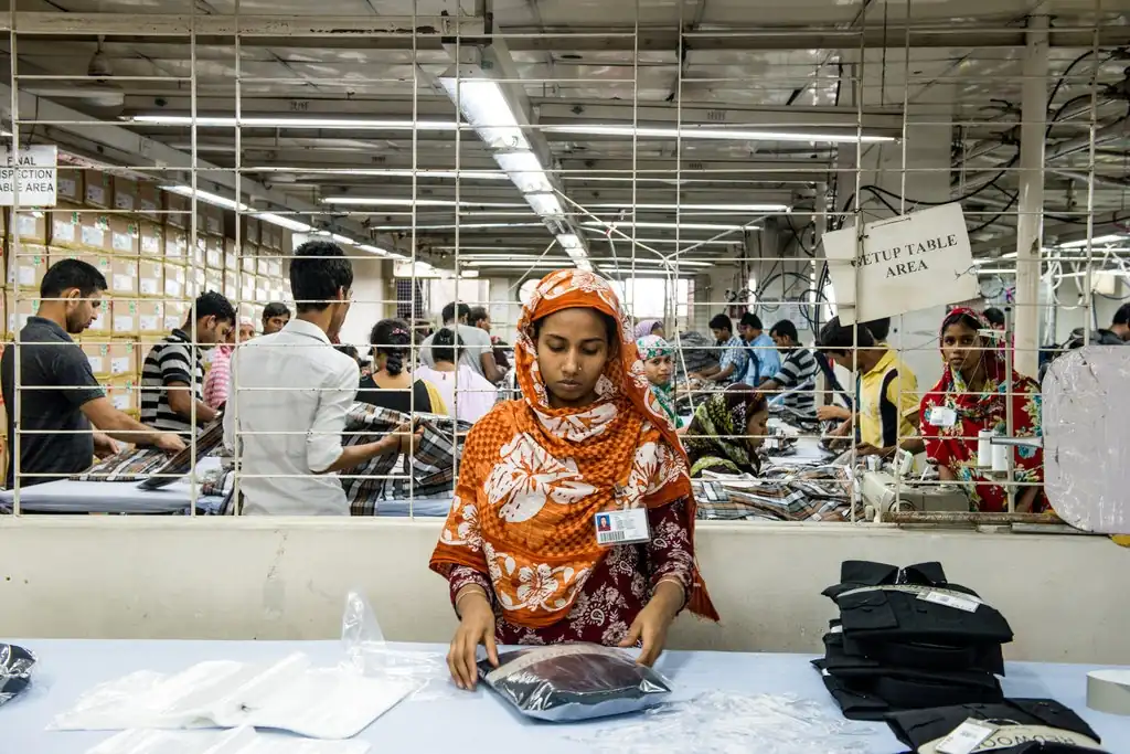 Operator folding and quality-checking finished garments on the factory floor, Dhaka, Bangladesh, DRESSOURCE
