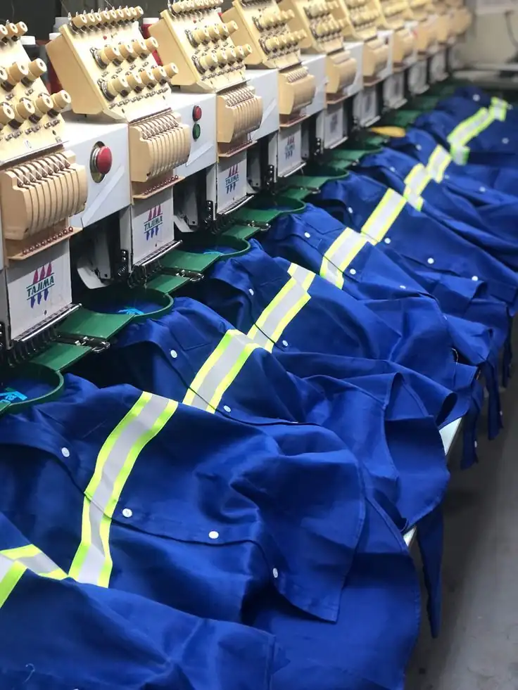 Embroidered hi-vis workwear jackets laid out under multi-head embroidery machines, garment manufacturer Dhaka, Bangladesh, DRESSOURCE