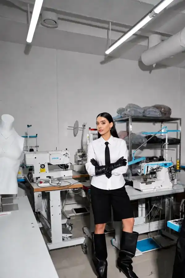 Model in a sample room beside a sewing machine, bulk garment production and cut-and-sew manufacturing, DRESSOURCE